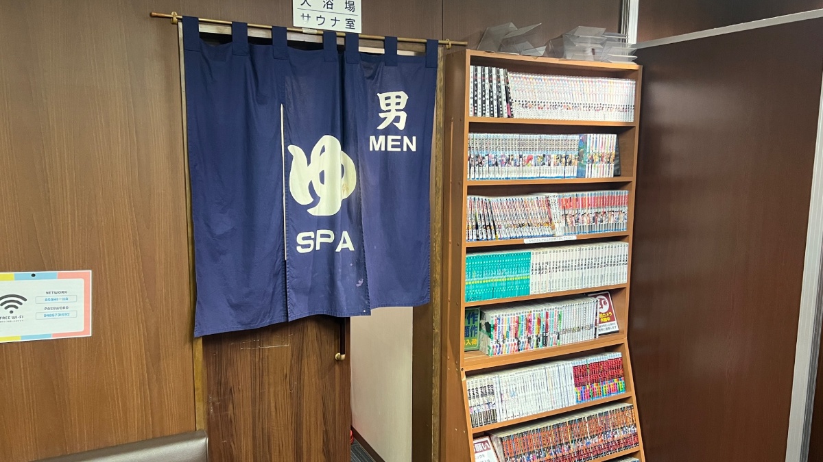 ビジネスホテルあさひの大浴場入口（男性用のれん・漫画棚）