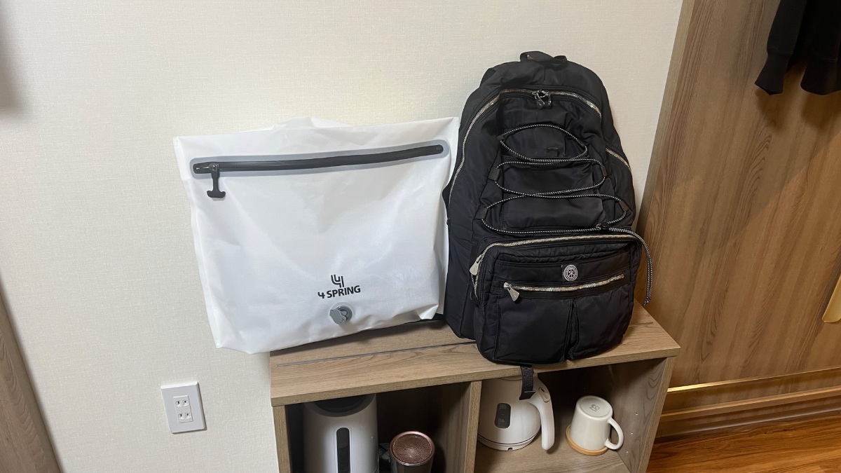 ホテル川六エルステージ高松の荷物置きスペースにバックパックとランドリーバッグを並べた様子